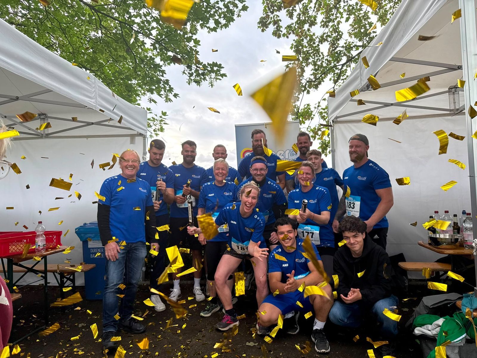 Jubelndes Mager-Team mit Goldkonfetti nach dem Zieleinlauf beim Dürener Firmenlauf 2026