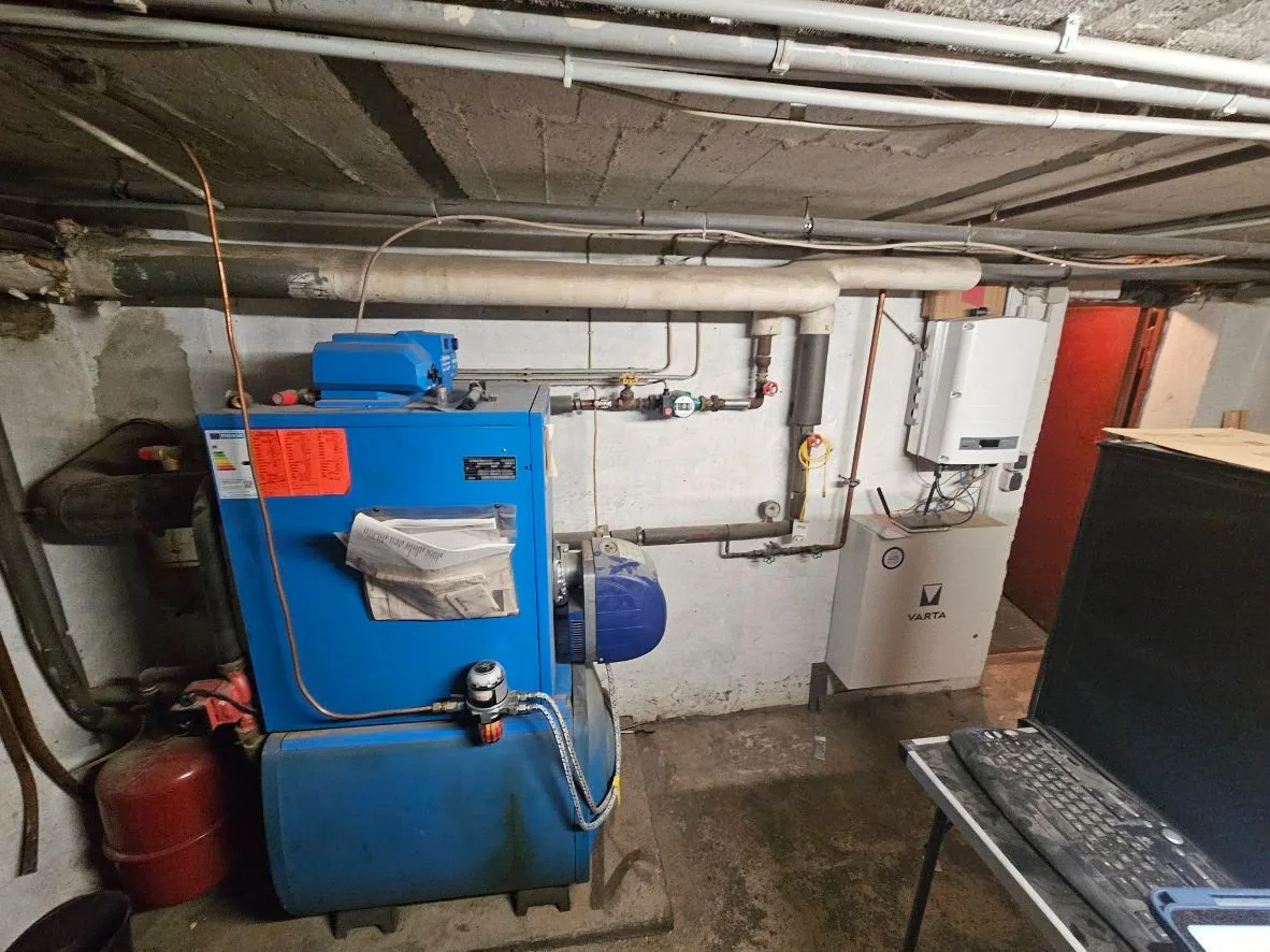 Vorher: alte blaue Öl-Heizung im Keller mit Öltank und rotem Ausdehnungsgefäß